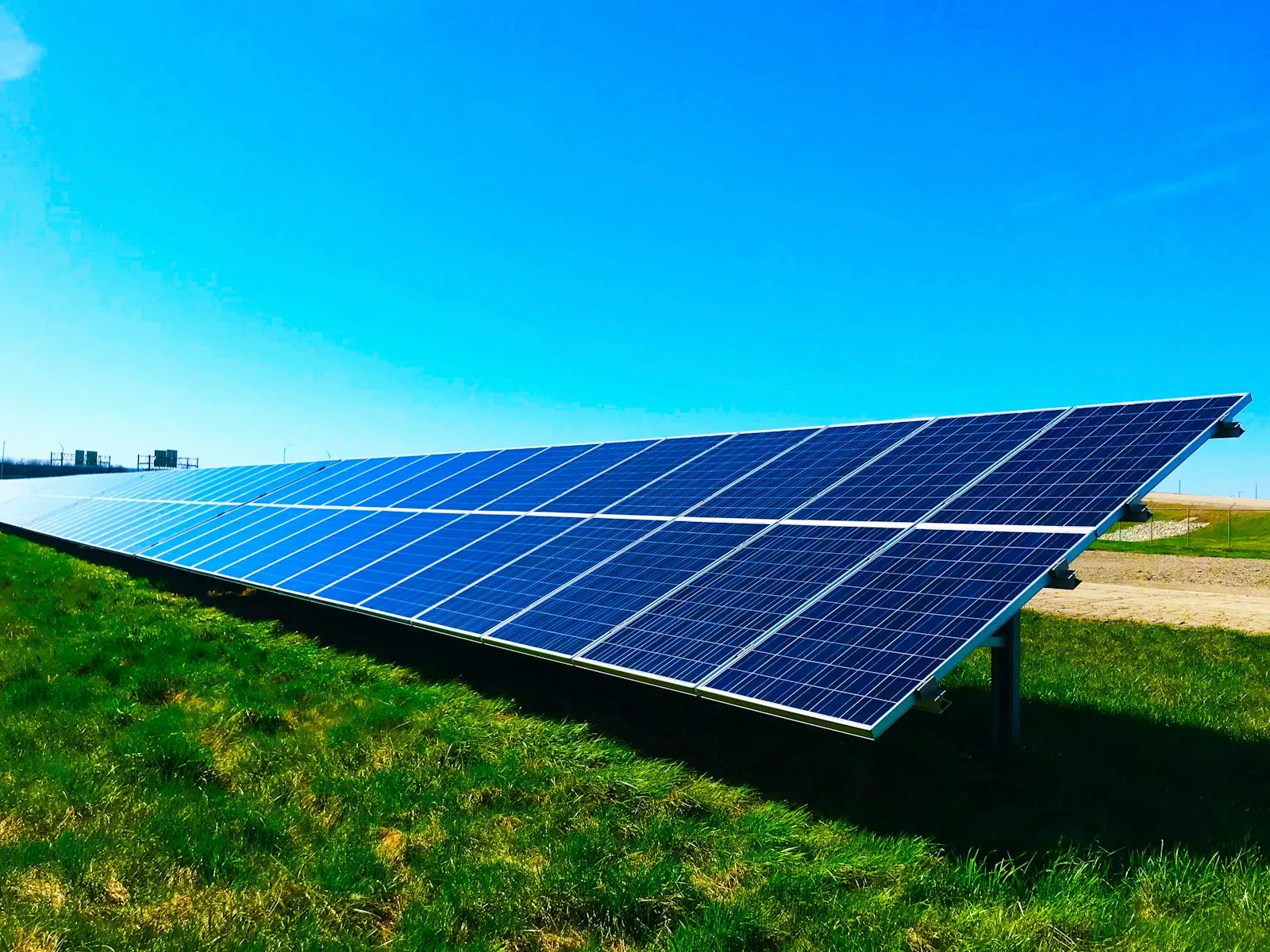 Große Photovoltaik-Freiflächenanlage auf grüner Wiese unter blauem Himmel